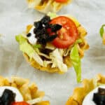 A tray o f the appetizer with lettuce, tomatoes, and sour cream.