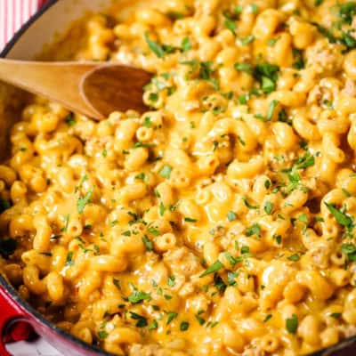 Veal cheeseburger macaroni in a red skillet with a wooden spoon