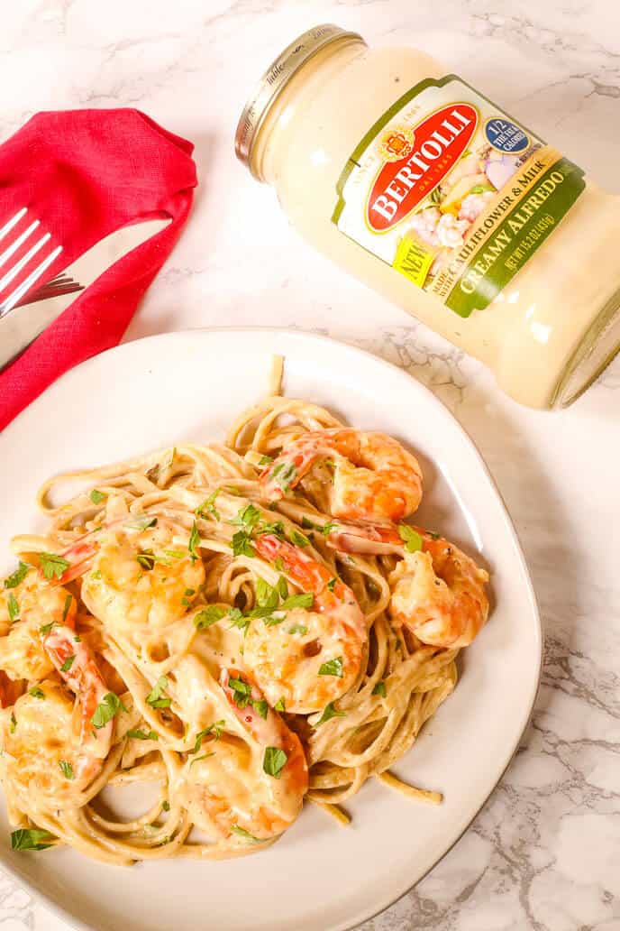 Shrimp alfredo recipe with red napkin and jar of bertolli sauce
