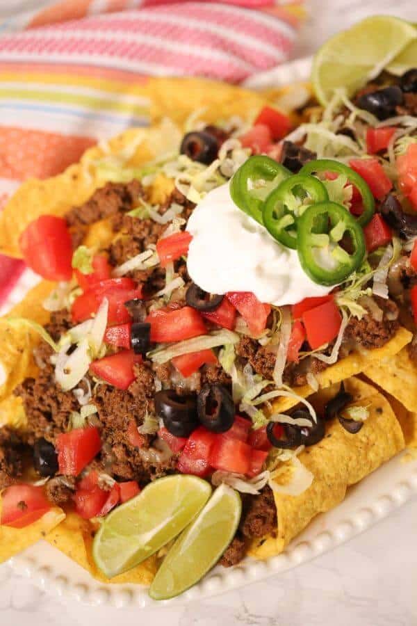 Beef sausage nachos on a white plate with colored napkin