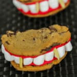 Two monster mouths with marshmallow teeth and red icing, placed on a dark textured surface.