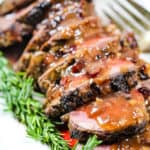 Beef tenderloin recipe on a white platter with rosemary