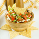 Salsa in a wooden bowl with tortilla chips.