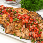 Grilled Chicken breast with strawberry salsa on a white plate.