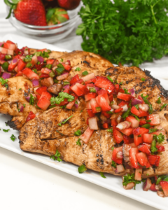 Grilled Chicken breast with strawberry salsa on a white plate.