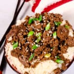 Beef Bulgogi over rice in a black bowl with red and white striped napkin