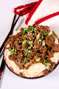 Beef Bulgogi over rice in a black bowl with red and white striped napkin
