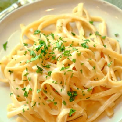 Fettuccine Alfredo on white plate with parsley