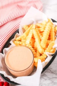 Basket of fries with red and white stripped napkin with fry sauce