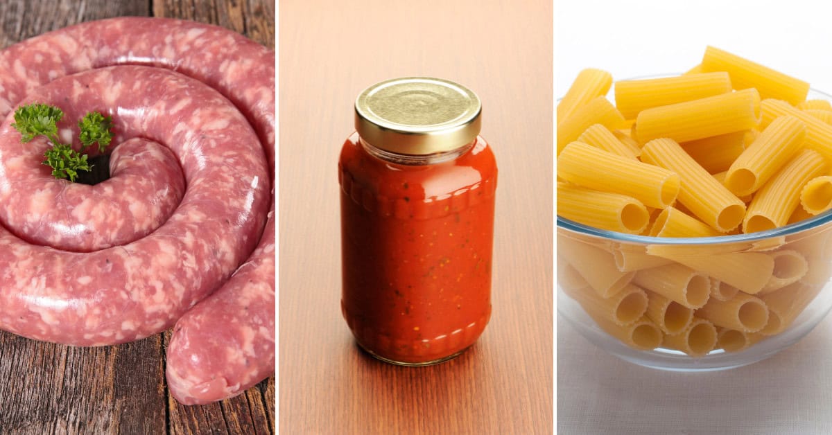Italian pork sausage links rest on a wooden surface beside a jar of rich red tomato sauce and a bowl of uncooked rigatoni, ready to be transformed into an authentic pasta dish.