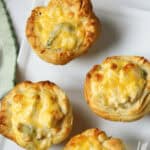 Three golden-brown chicken pot pie quiches on a white plate.