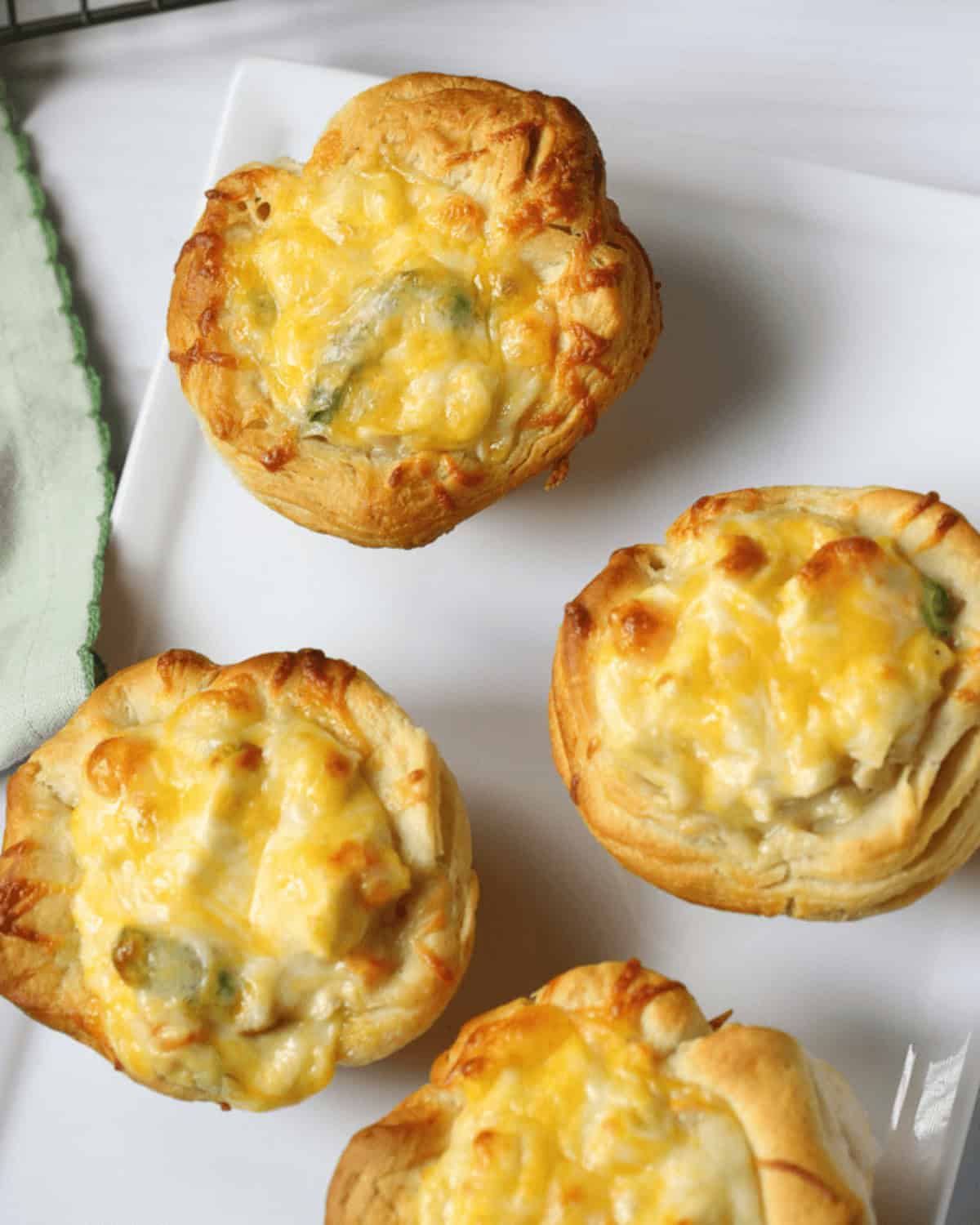 Three golden-brown chicken pot pie quiches on a white plate.