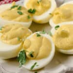 A plate of fancy deviled eggs garnished with fresh herbs.