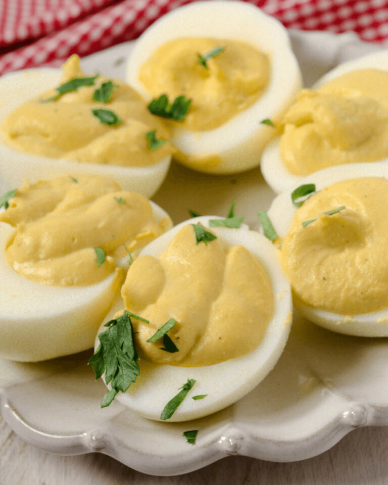 A plate of fancy deviled eggs garnished with fresh herbs.