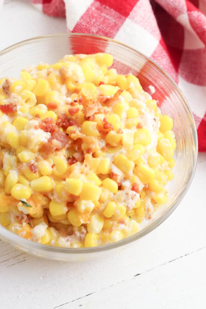 Cheesy Corn and bacon casserole in a bowl with a checkered towel