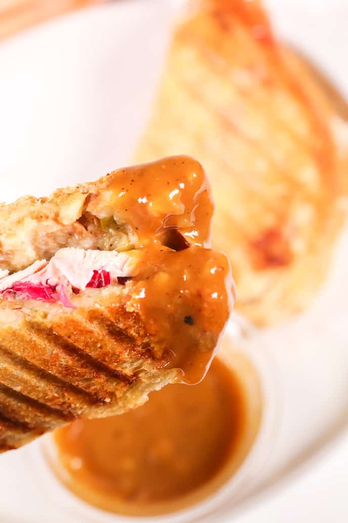 A close up  of Leftover thanksgiving turkey panini that has been dipped in gravy