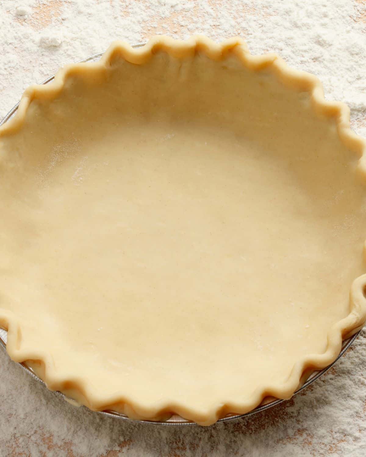 Unbaked pie crust in a dish, ready for a ham and cheese and spinach quiche filling.