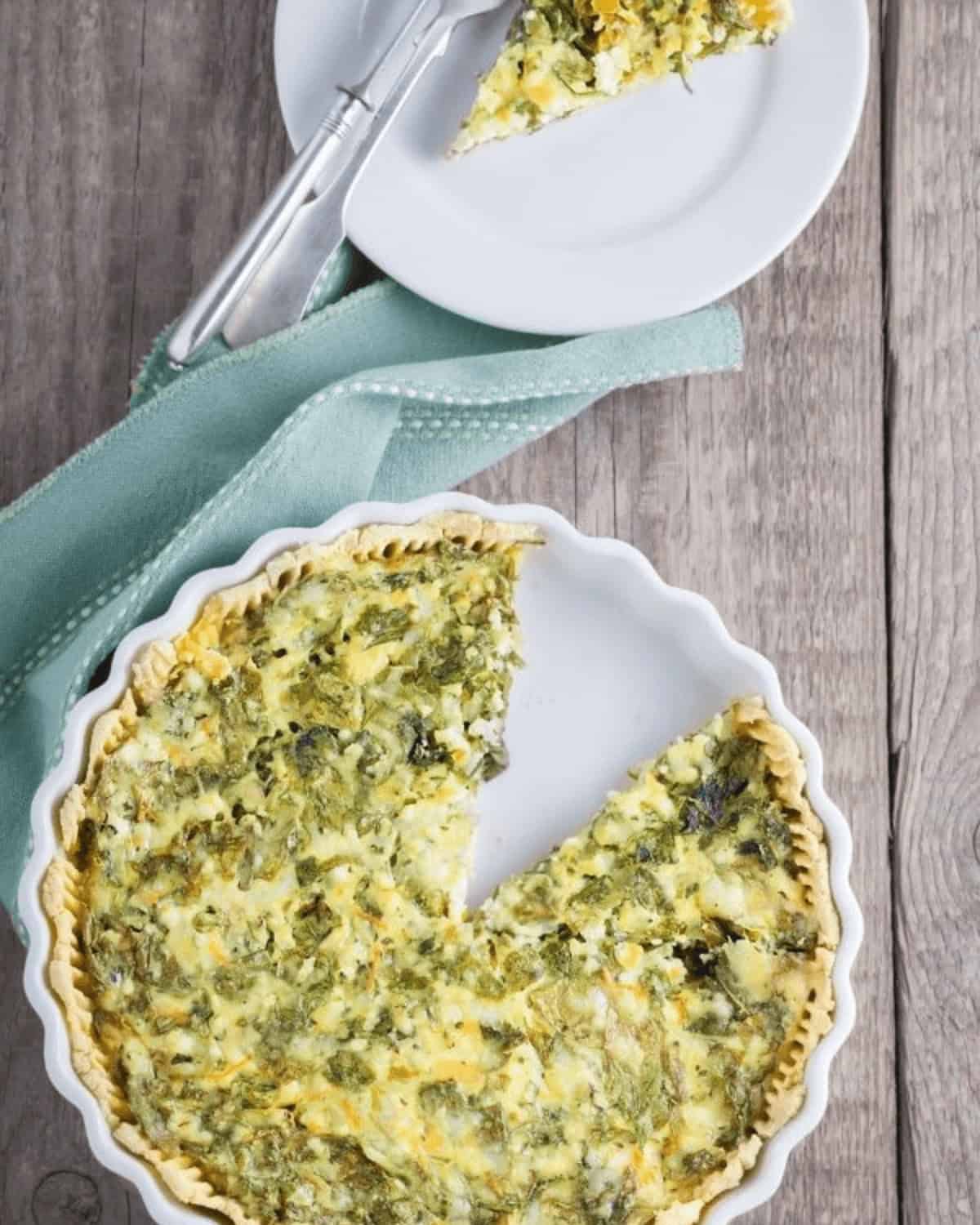 A homemade ham and cheese quiche with a slice served on a plate, featuring a wooden table backdrop.