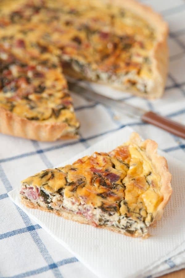 Ham, Cheese and Spinach Quiche on a plaid  blue tablecloth