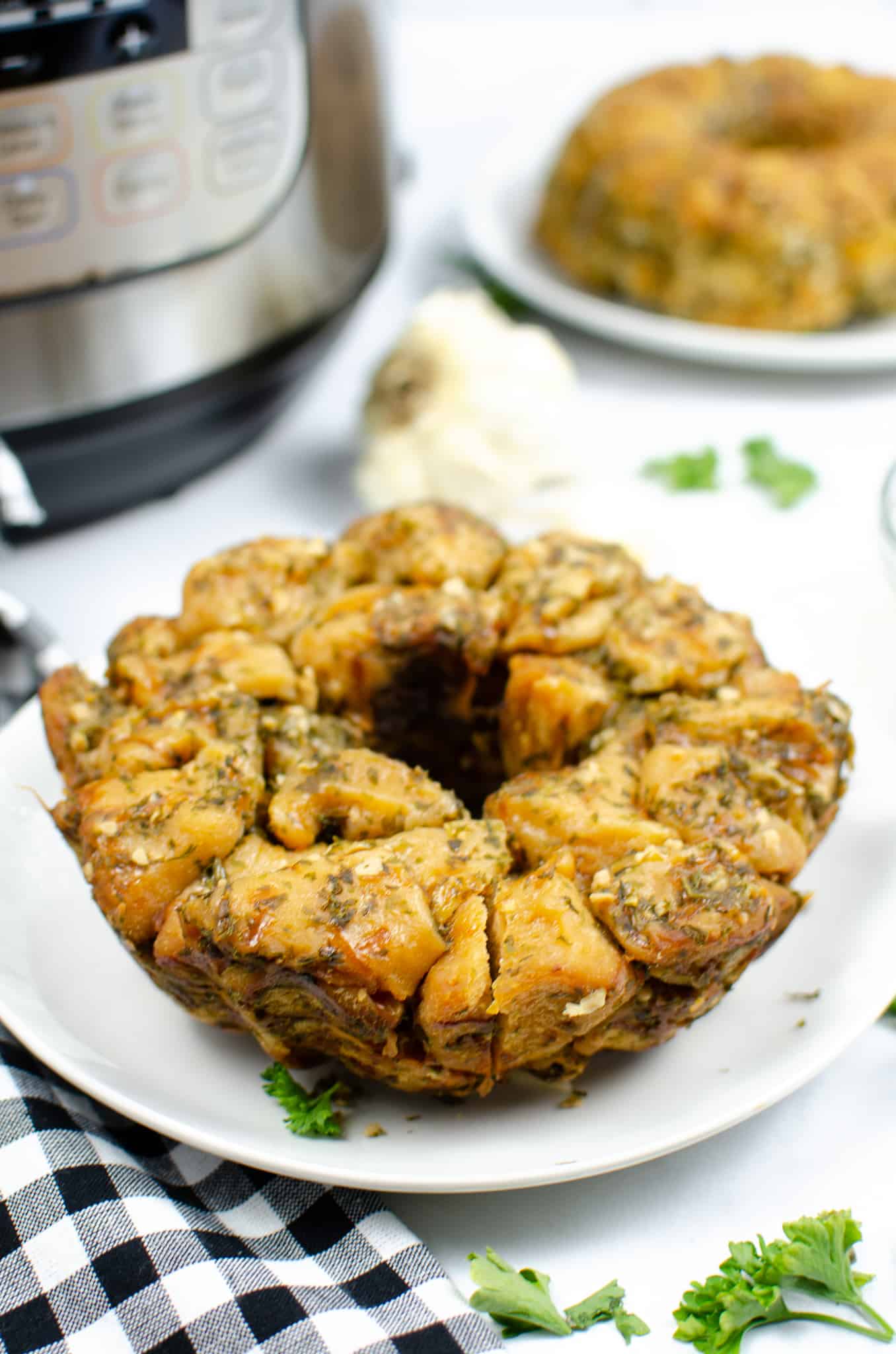 Instant pot garlic monkey bread recipe on white plate with a black checkered napkin and an instant pot in the background