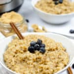 Instant Pot Maple and Brown sugarOatmeal in a white bowl with a cinnamon stick and blueberries