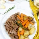 Instant Pot Pot Roast on a white plate with a yellow polka dot napkin and a sprig of thyme