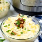Instant Pot Potato Soup in a clear bowl topped with bacon and herbs