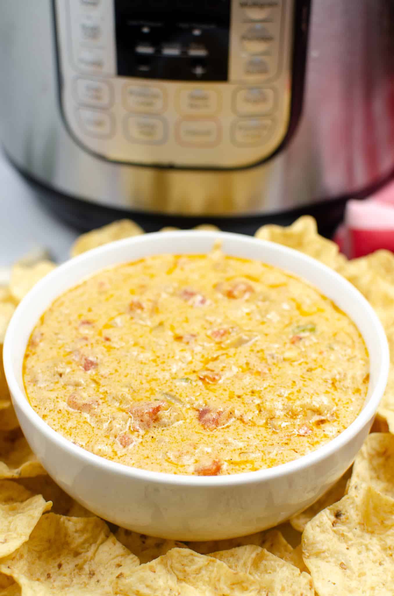 White bowl filled with Instant Pot Queso with Meat and surrounded by chips