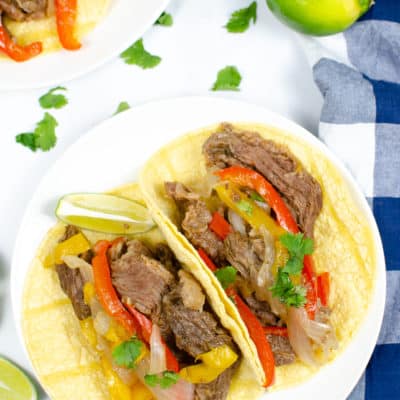 Steak Fajitas in shells on white plate with blue and white check napkin
