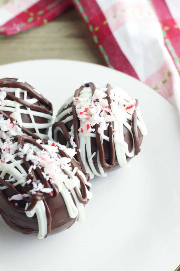 Hot chocolate bombs on a white plate with a red plaid napkin on the side. 