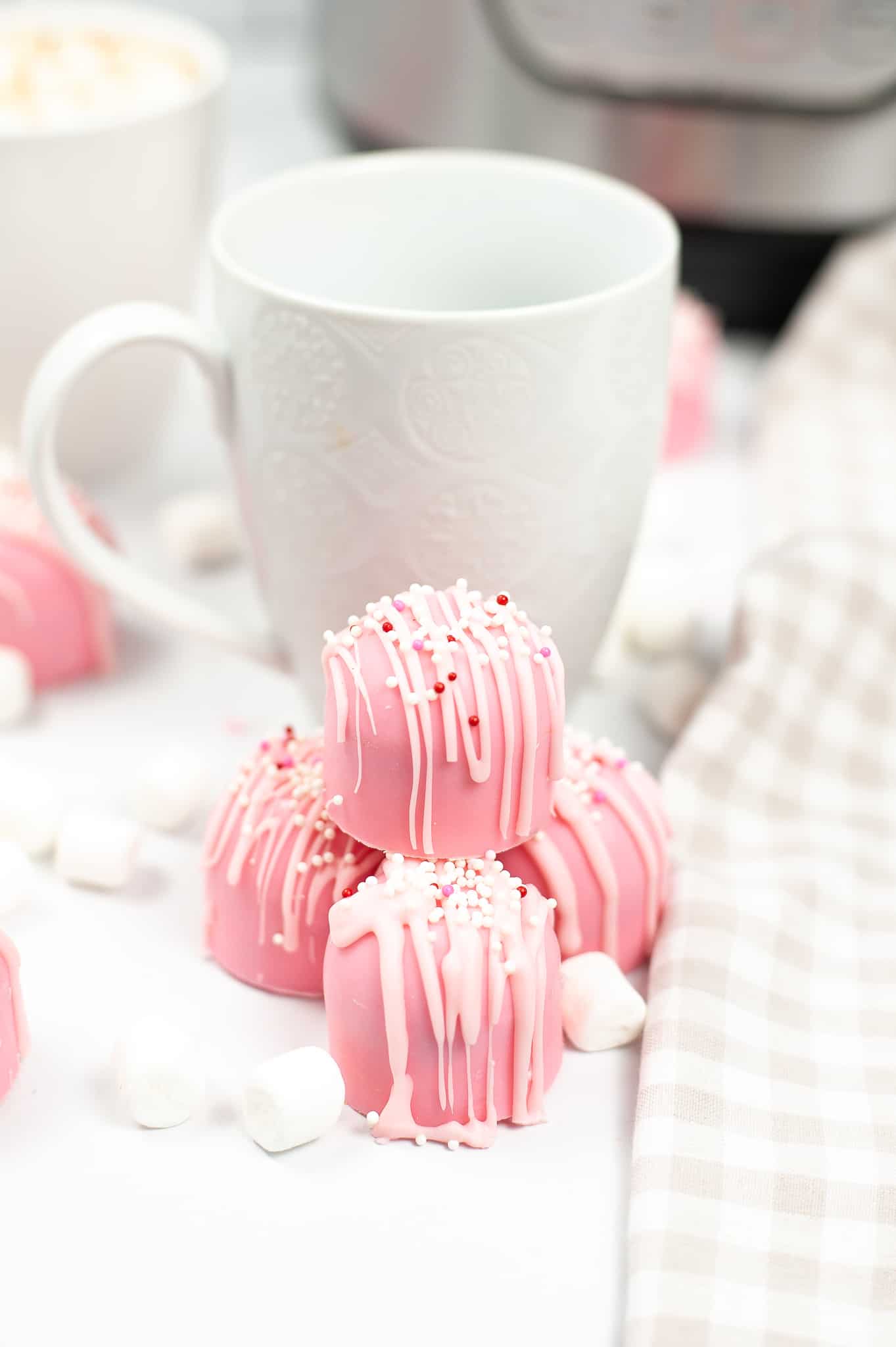 Pink Cupid Hot Cocoa Bombs with a white mug in the background