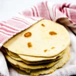 Homemade flour tortillas wrapped in a red and white towel