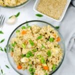 A bowl of Instant Pot chicken fried rice with peas, carrots, scrambled egg, and green onions, served beside a small dish of sesame seeds on a white surface.