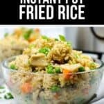 A glass bowl filled with Instant Pot chicken fried rice, featuring peas, carrots, and green onions, sits on a white surface.