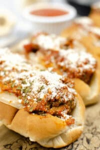 Close-up of a meatball subs recipe, showcasing delicious subs topped with marinara sauce and grated cheese on a wooden board.