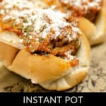 Close-up of a delicious meatball subs recipe, featuring meatballs smothered in tomato sauce and topped with grated cheese, all on a wooden surface. Text overlay reads "Instant Pot Meatball Subs.