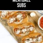Four meatball subs topped with Parmesan and herbs rest on a wooden board, alongside a bowl of tomato sauce and a clove of garlic. Text above reads "Instant Pot Meatball Subs Recipe.