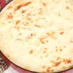 Ground beef, featuring a golden mashed potato topping in a red skillet on a marble surface.