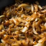 Close up on fried onions in a frying pan.