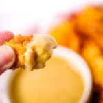 Close up of a hand holding a piece of chicken with chick fila sauce on it