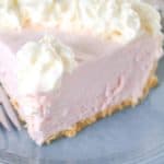 Slice of pink lemonade pie on a blue plate with a fork.