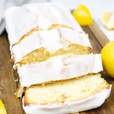Close up shot of starbucks lemon loaf on a woooden cutting board surrounded by lemons