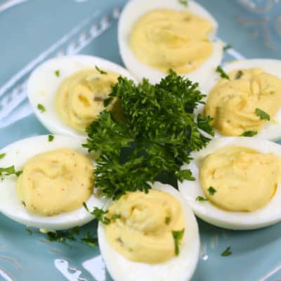 Traditional Southern Deviled Eggs on a blue plate with fresh herbs
