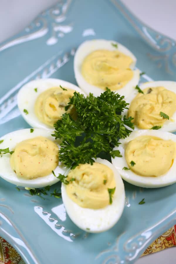 Traditional Southern Deviled Eggs on a blue plate with fresh herbs