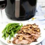 Steak and Mushrooms on a white plate with green beans. An Air Fryer is in the background.
