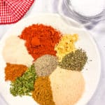 All the spices needed for the spice blend on a white dish