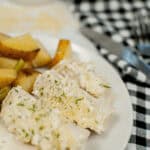 A plate of creamy pasta, topped with herbs and grated cheese, sits invitingly next to roasted potato wedges on a black and white checkered tablecloth. It's the perfect companion to a delightful evening featuring sheet pan chicken with vegetables.