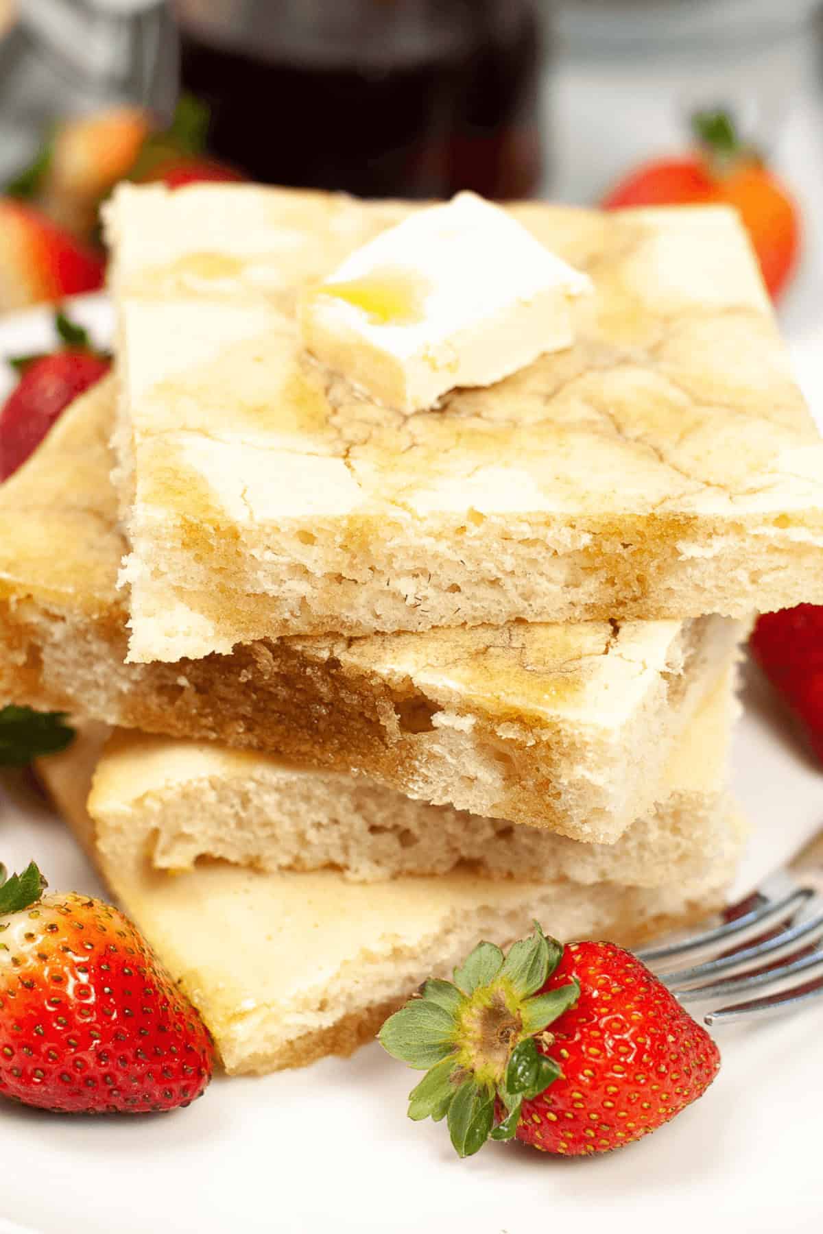 A stack of the sheetpan pancakes surrounded by berries.