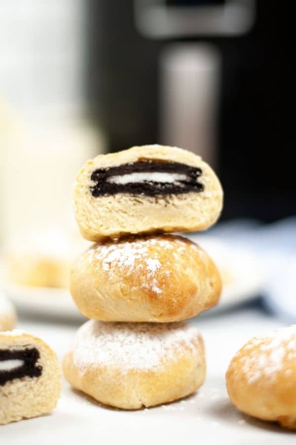 Air Fried oreos stacked on a plate with a cut open one on top revealing the oreo.