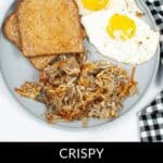 A plate with two pieces of toast, two sunny-side-up eggs, and crispy Air Fryer Hash Browns. A small bowl of fruit and a black-and-white checkered napkin are nearby.